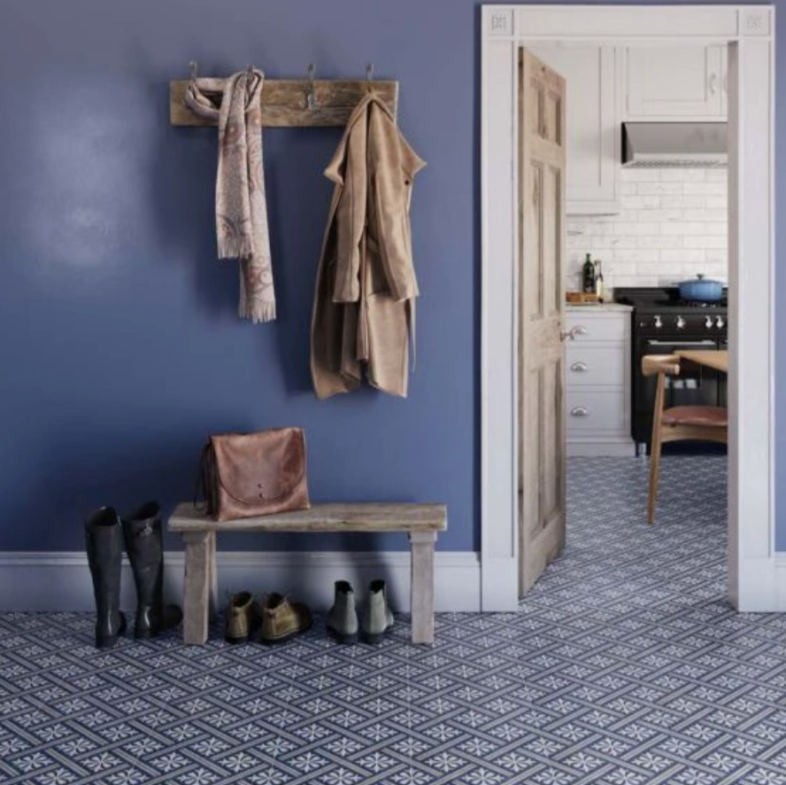 Entryway with wooden bench, coat rack, and shoes against a blue wall.